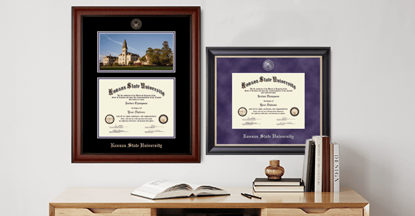 desk with books on it against a wall that features two diploma frames, one with a picture of a campus and a diploma and the other just a diploma.