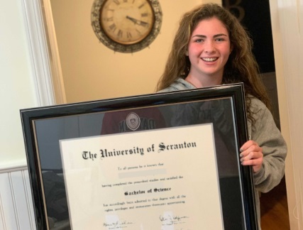 College graduate holding her custom diploma frame