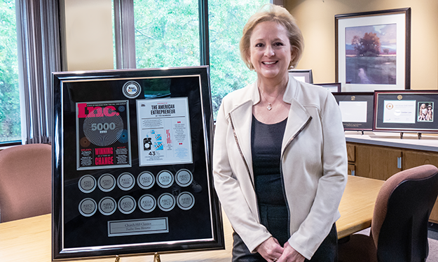 Church Hill Classics CEO Lucie Voves standing next to 12 time INC 5000 award-winning custom frame