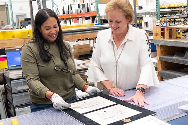 Church Hill Classics CEO Lucie Voves building a custom frame with framing professional employee