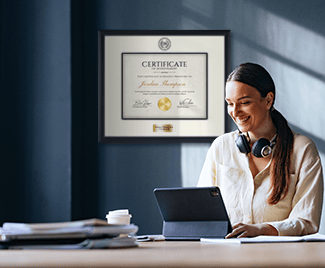 Credential certificate frame on wall behind woman working on computer