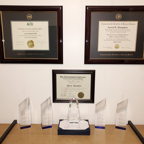 gallery wall of three custom certificate frames and five engraved crystal awards on table 