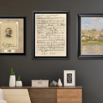 three framed art pieces in black frames above chair, plant, and dresser