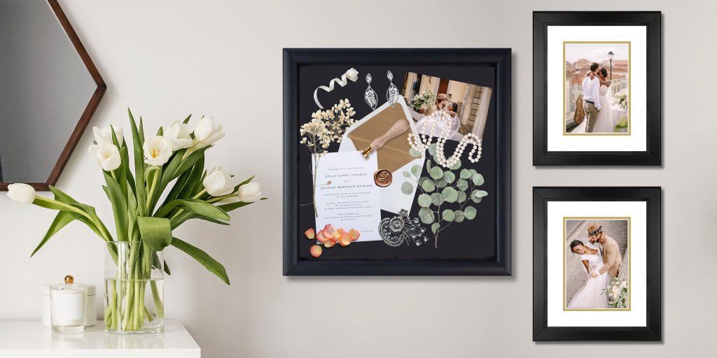 wall with wedding photos and shadow box filled with memorabilia next to plant and mirror