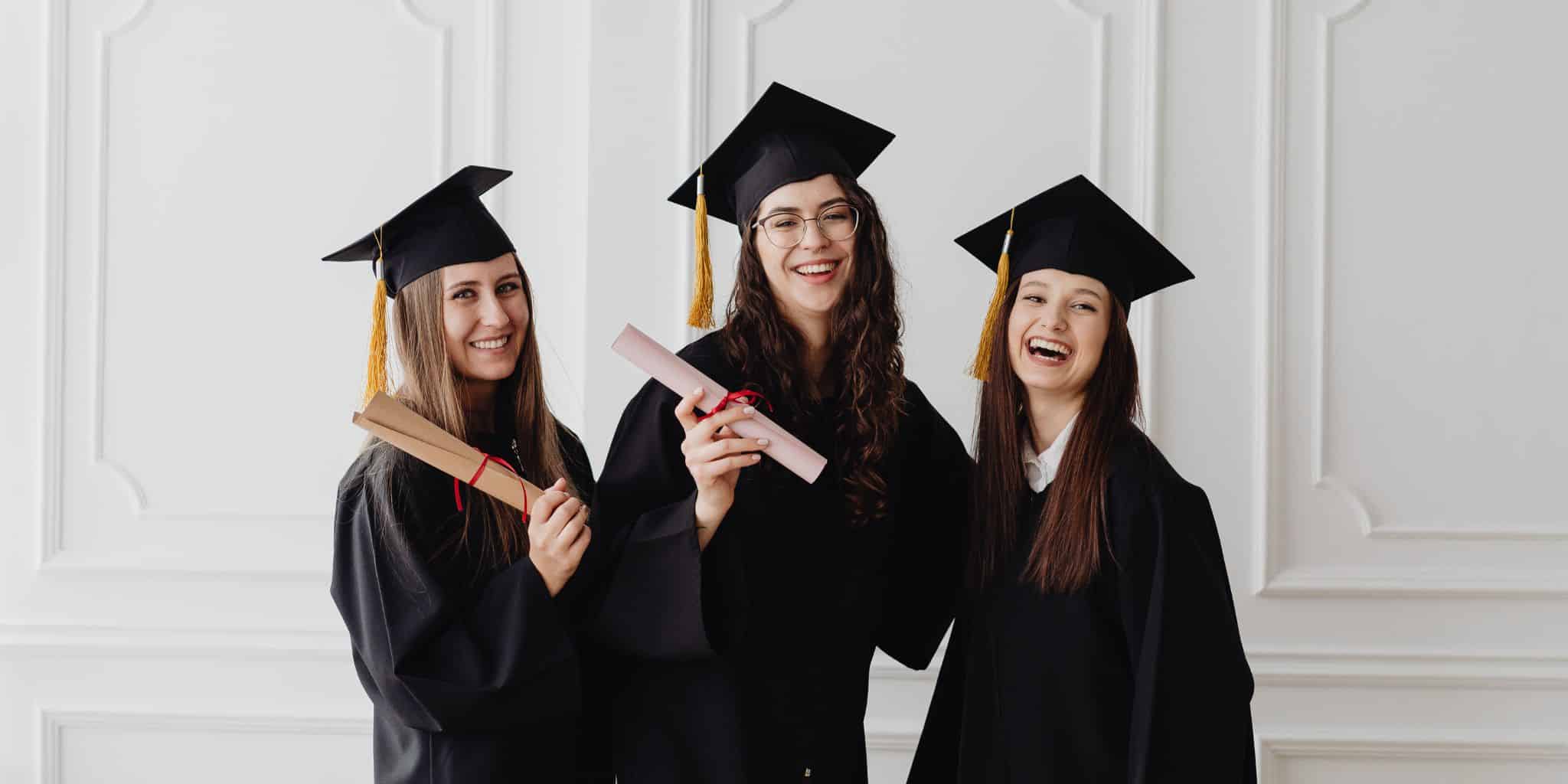 three female grads with rolled diplomas