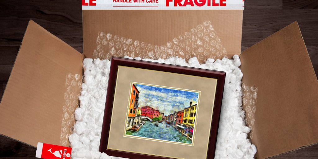 Framed artwork sitting in shipping box with packing peanuts and bubblewrap