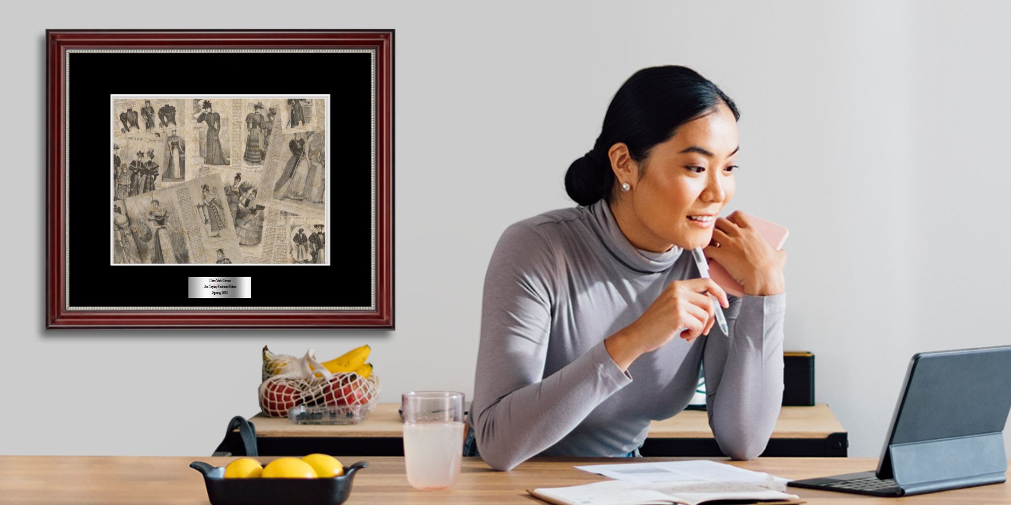 woman at desk with framed historic newspaper clipping on wall