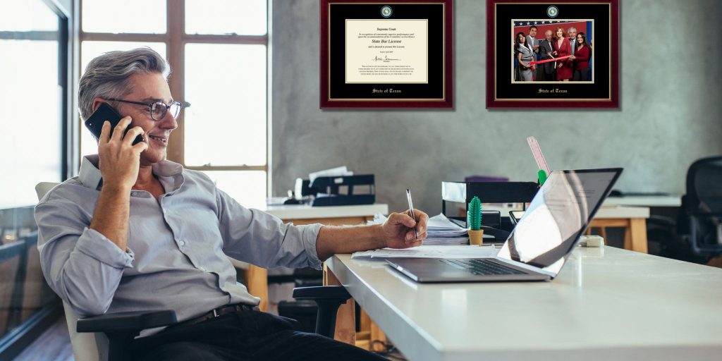 man on phone writing on paper on desk in office