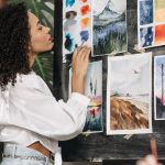 woman reviewing watercolor paintings on wall
