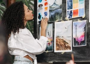 woman reviewing watercolor paintings on wall