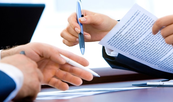 closeup of hands holding pens with contract