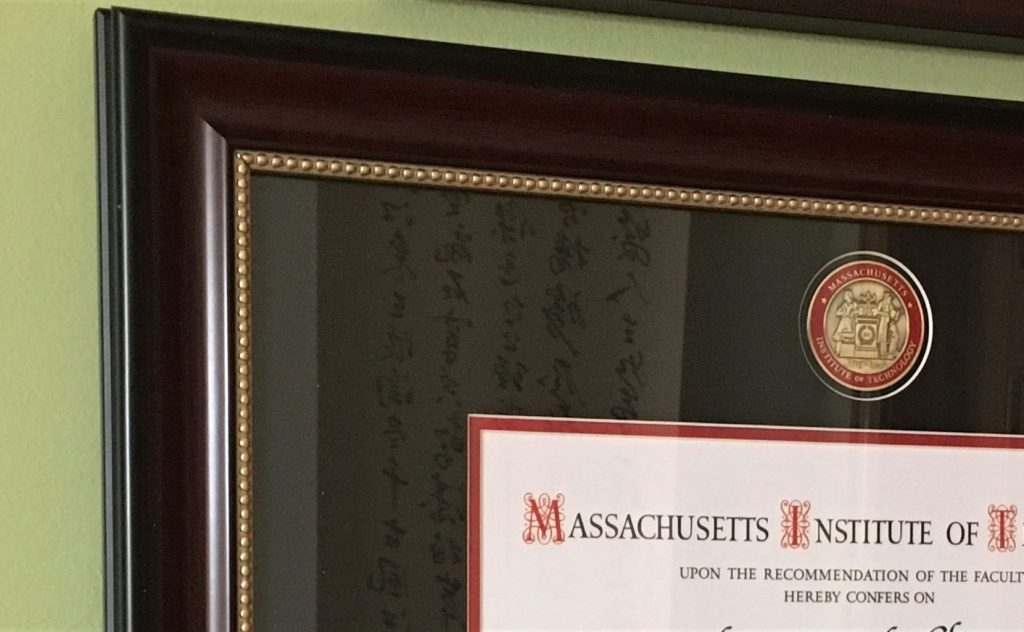 Closeup of MIT degree frame hanging on a green wall