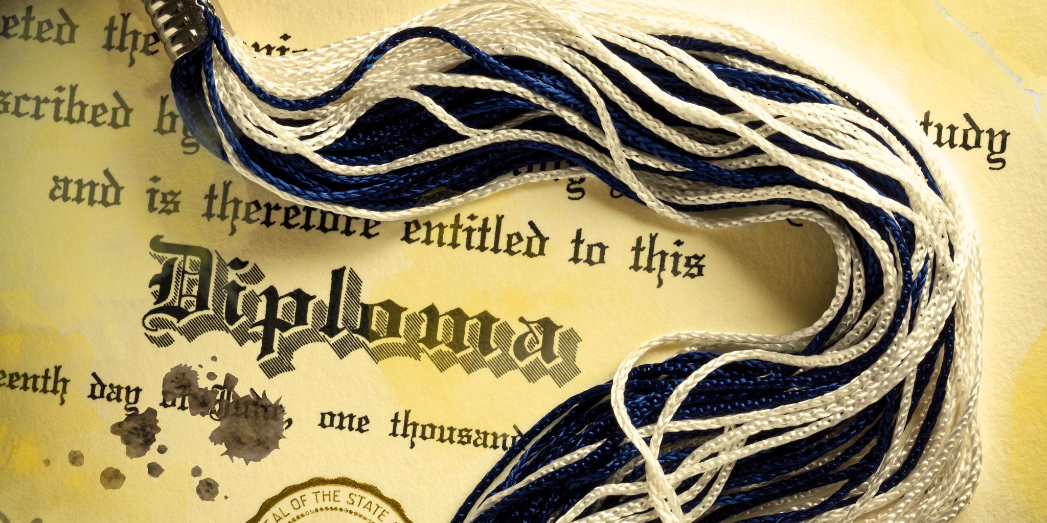 closeup of yellow stained diploma with tassel on it