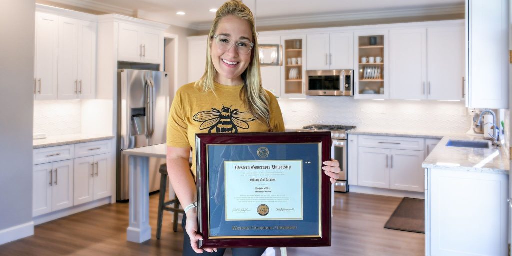 person holding western governors university diploma frame in kitchen