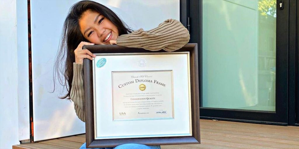 girl smiling and holding custom diploma frame