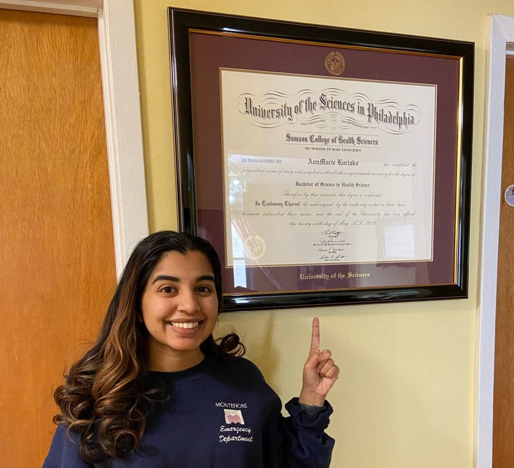 girl pointing to her uscience of philly diploma frame