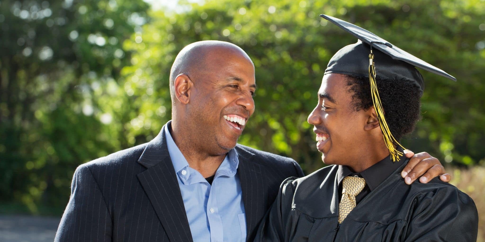 father smiling at graduate son