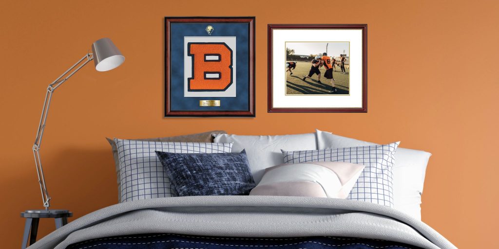 bedroom with varsity letter shadow box and custom photo frame above bed on orange wall