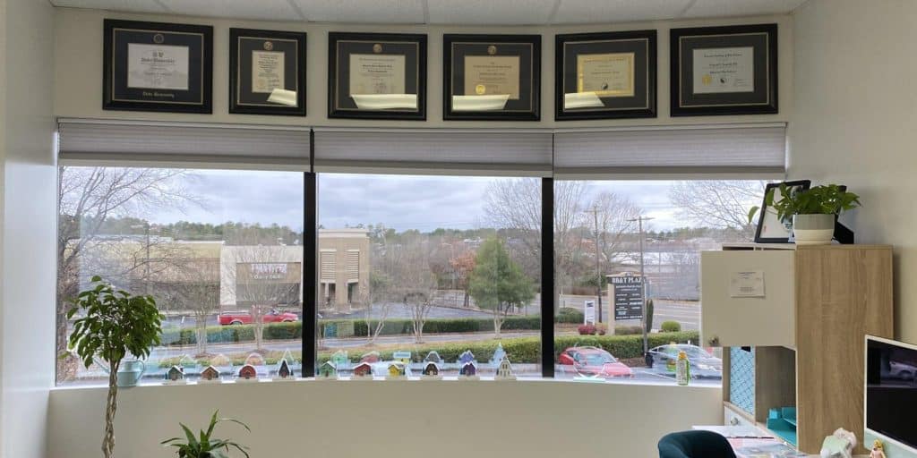 six diploma frames on office wall above window