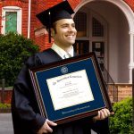 graduate smiling holding uconn diploma frame