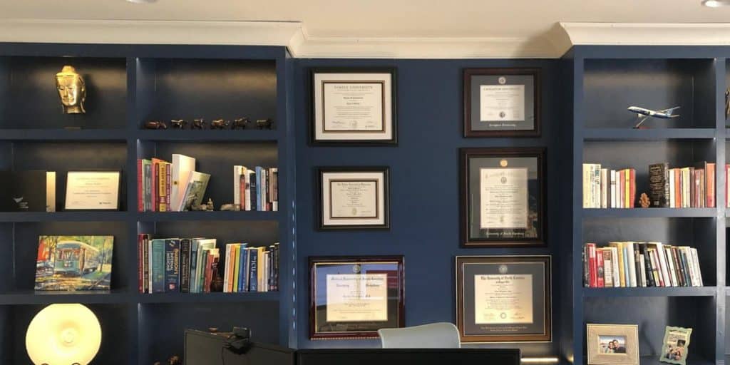 blue office with shelves and six diploma frames on wall