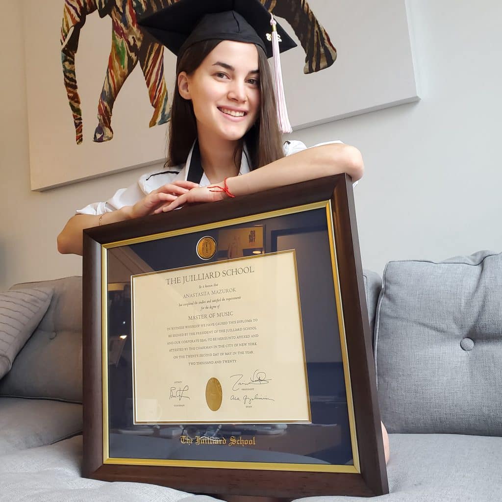 smiling grad on couch with juilliard frame