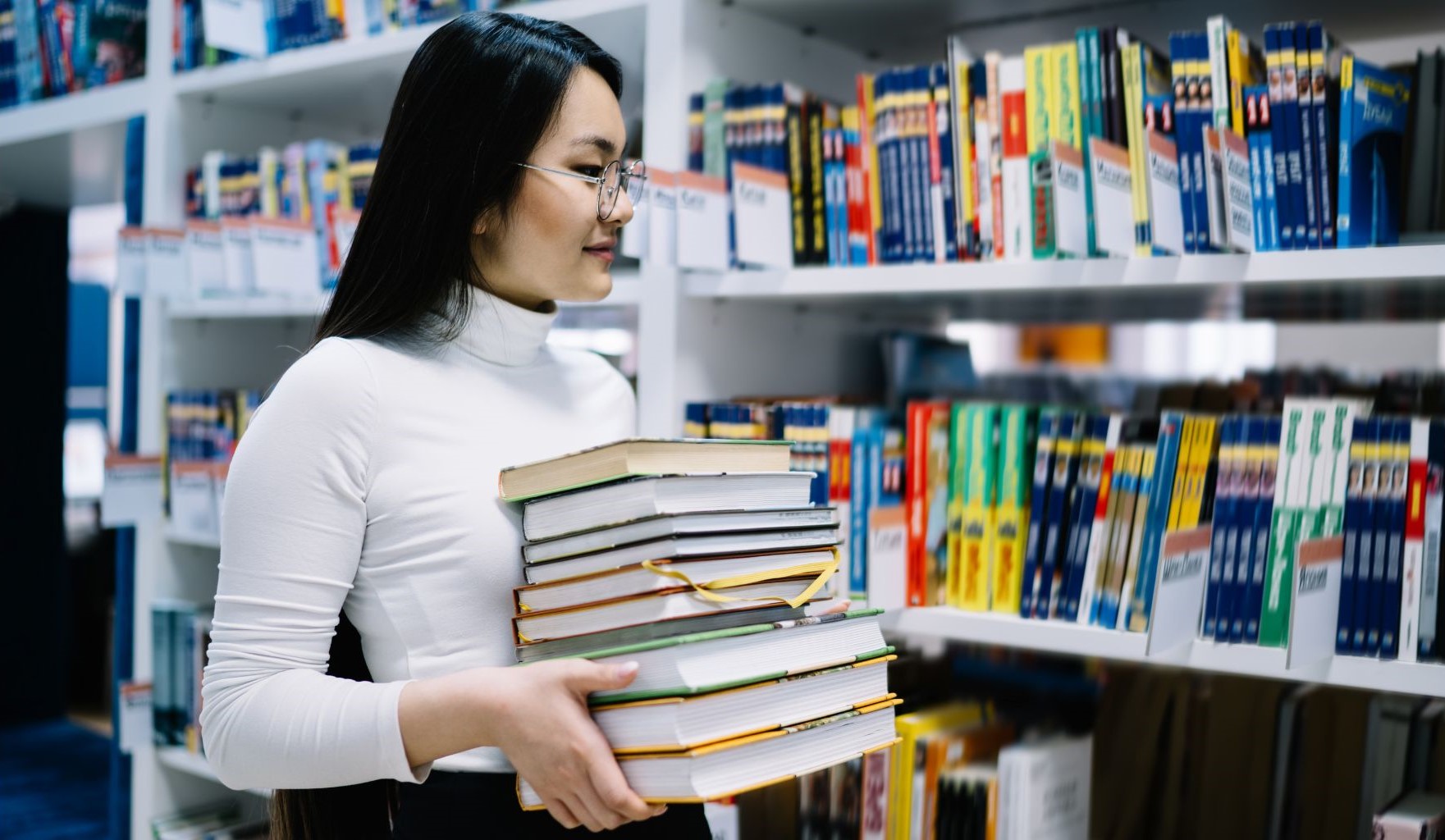 woman holding books looking at used books on shelf store