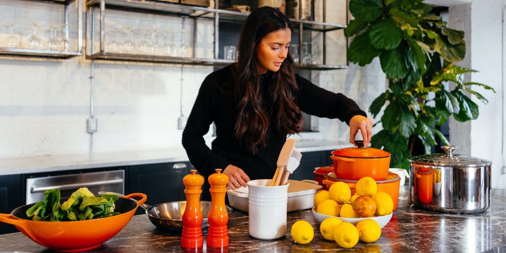 woman in black shirt cooking in kitchen with ingredients on counter