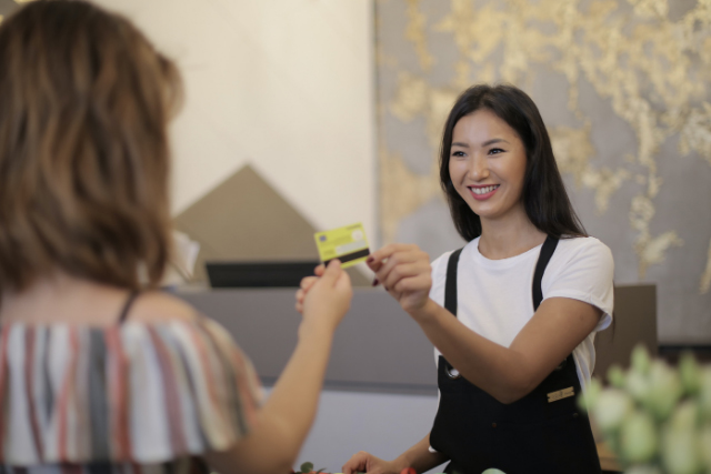 girl handing over card to smiling cashier