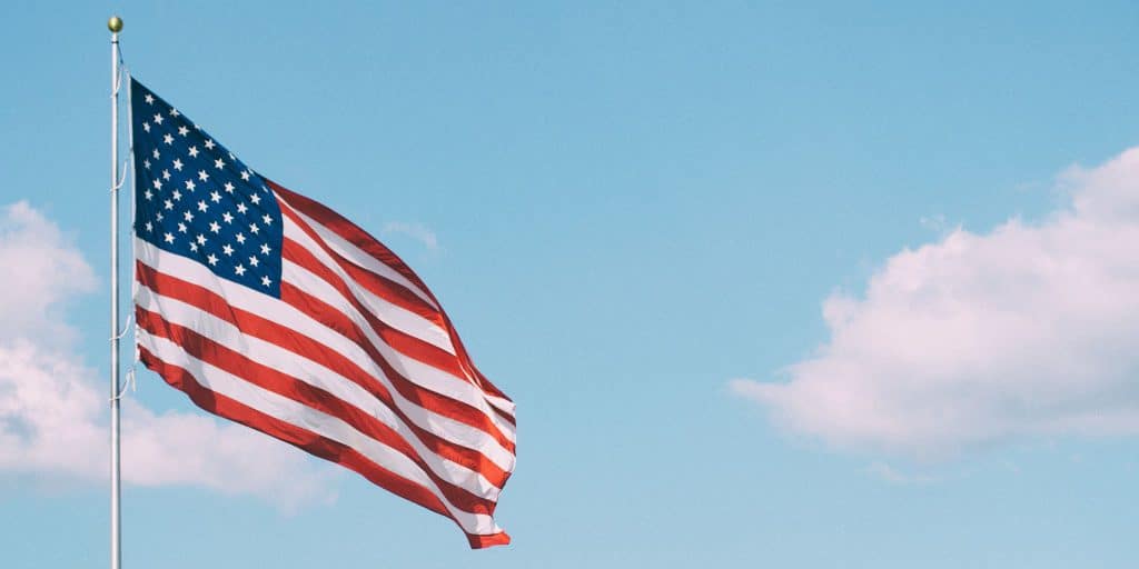 American flag on pole with blue sky behind it