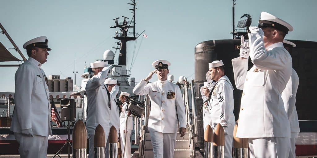 US navy officers in uniform saluting commander