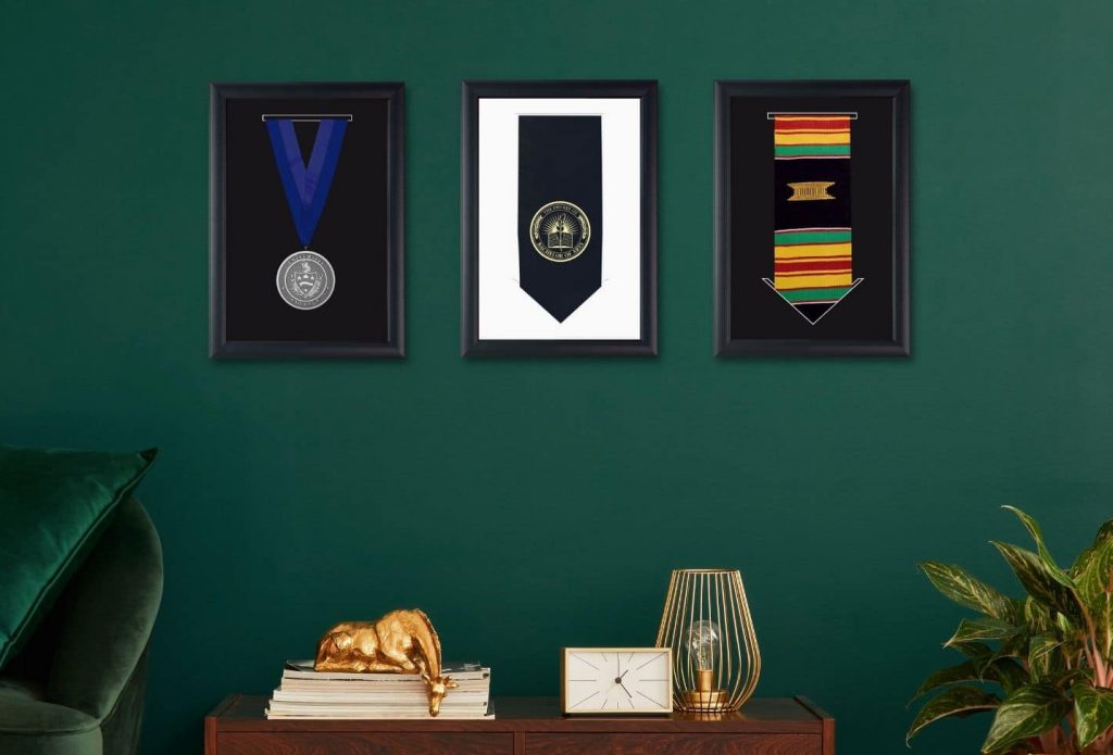framed graduation medals and stoles on green wall