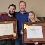 father with kids both holding UT austin diploma frames