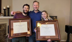 father with kids both holding UT austin diploma frames