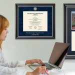 woman working on computer with custom diploma frames hung on wall in office