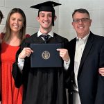 graduate holding diploma cover with family