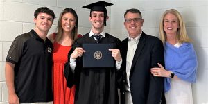 graduate holding diploma cover with family