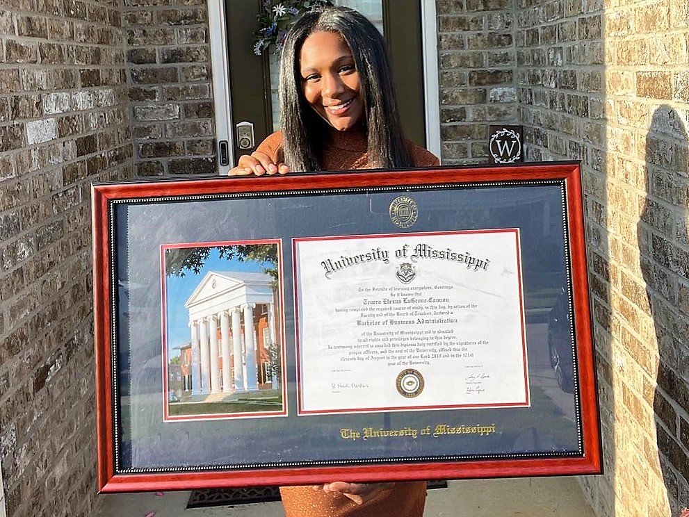 smiling woman holding huge University of Mississipi diploma frame featuring photo of Ole Miss Lyceum