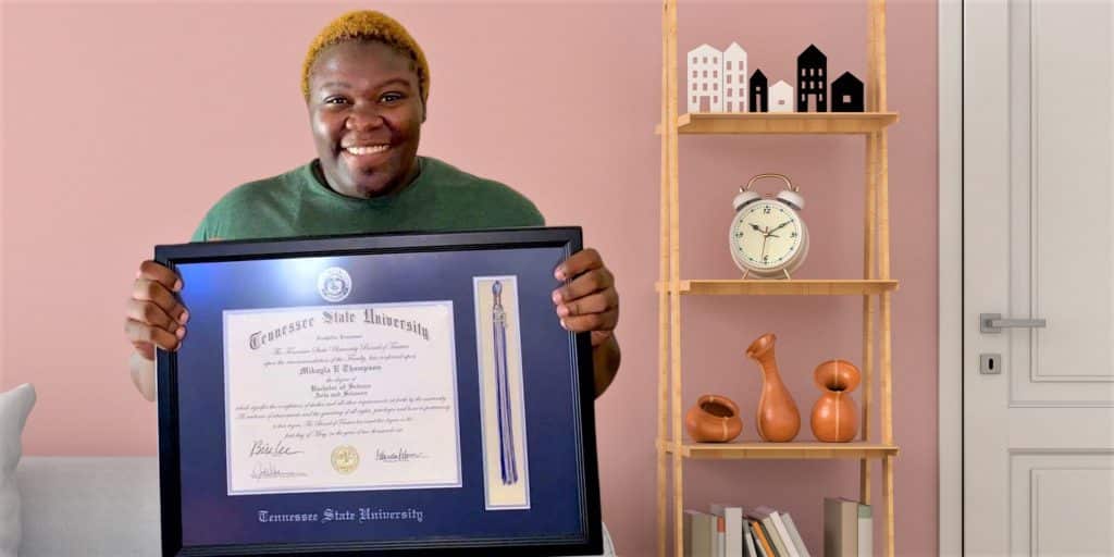 smiling HBCU grad holding Tennesee State University frame