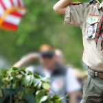 scout dressed in boy scout uniform saluting toward camera