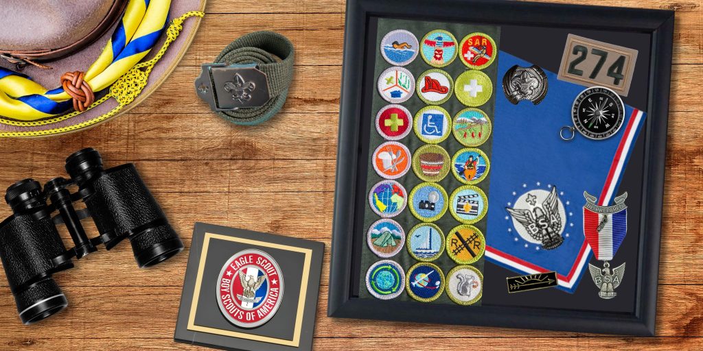 keepsake shadow box frame filled with eagle scout memorabilia and boy scouts paperweight on wooden table