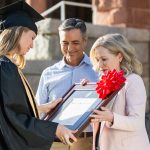mother and father gifting a custom diploma frame to their daughter in college graduation regalia