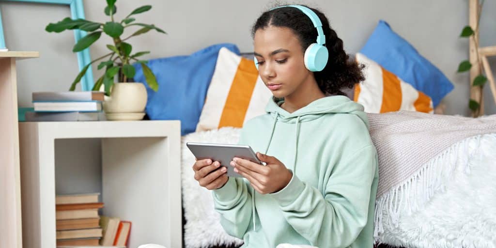 girl sitting on bedroom floor wearing mint green headphones