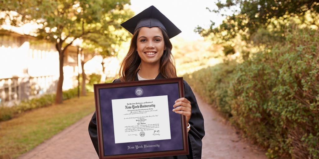 female NYU graduate posing with frame