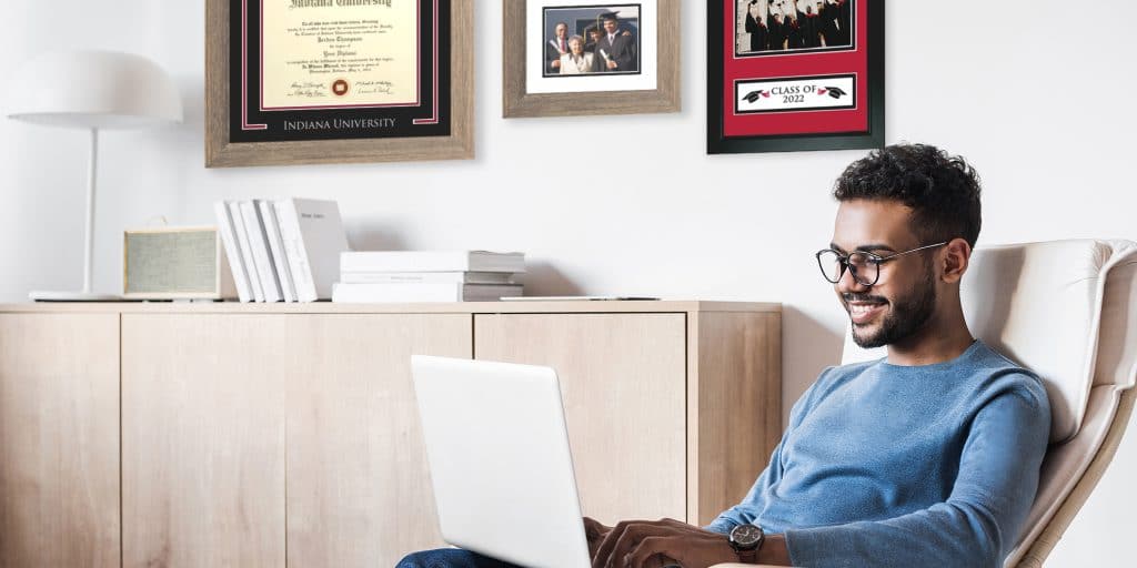 graduate working on computer with various chc frames in background