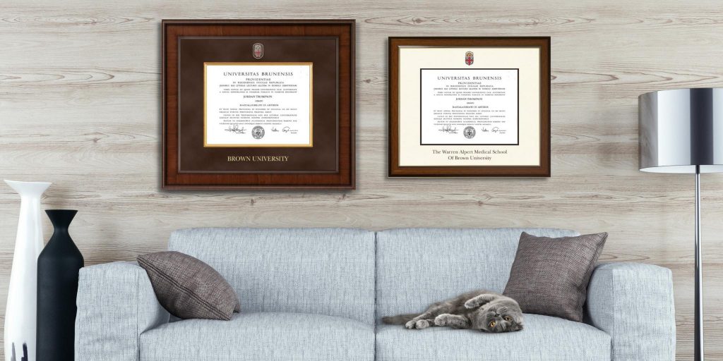 framed brown university degrees on wall above couch