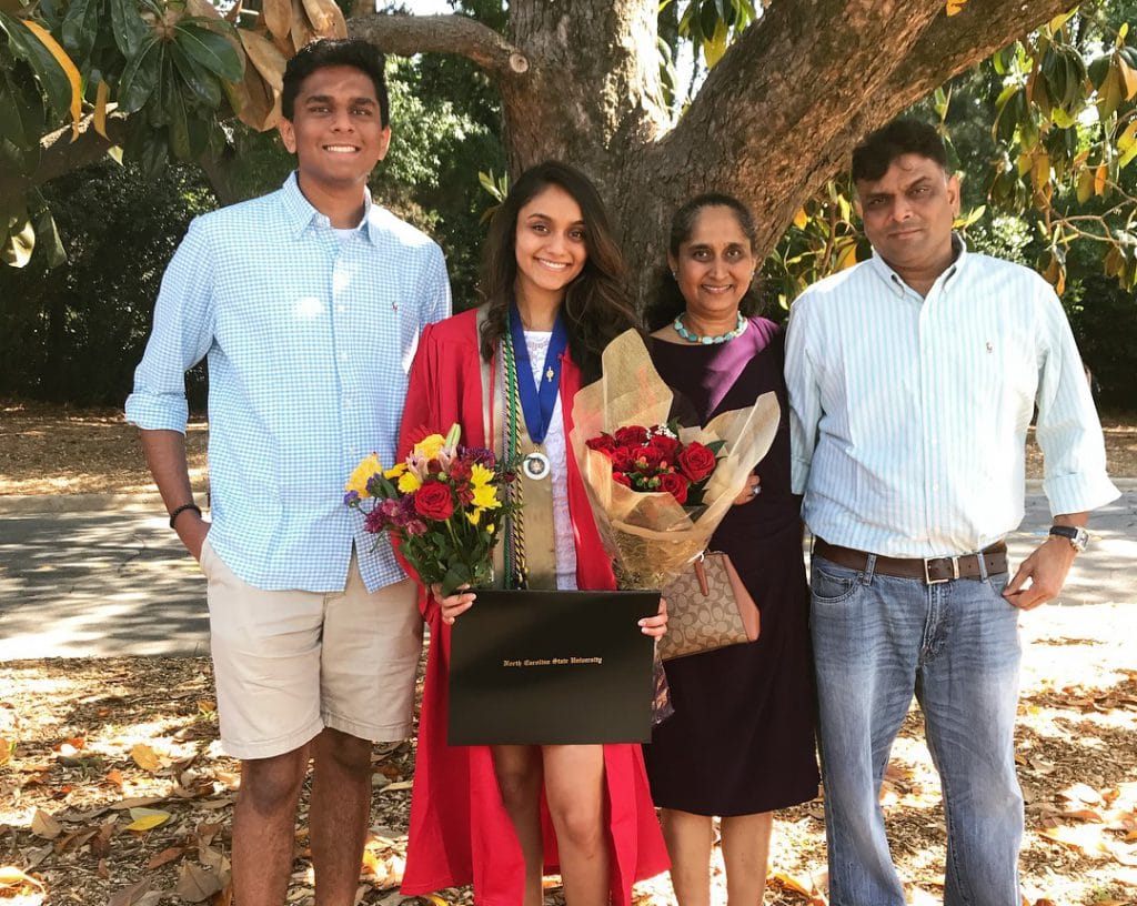 graduate holding flowers wearing honor medallion with family