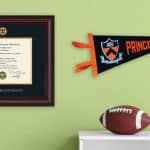 wall with princeton dipolma frame, spirit pennant, and photo frame with football player and football on desk