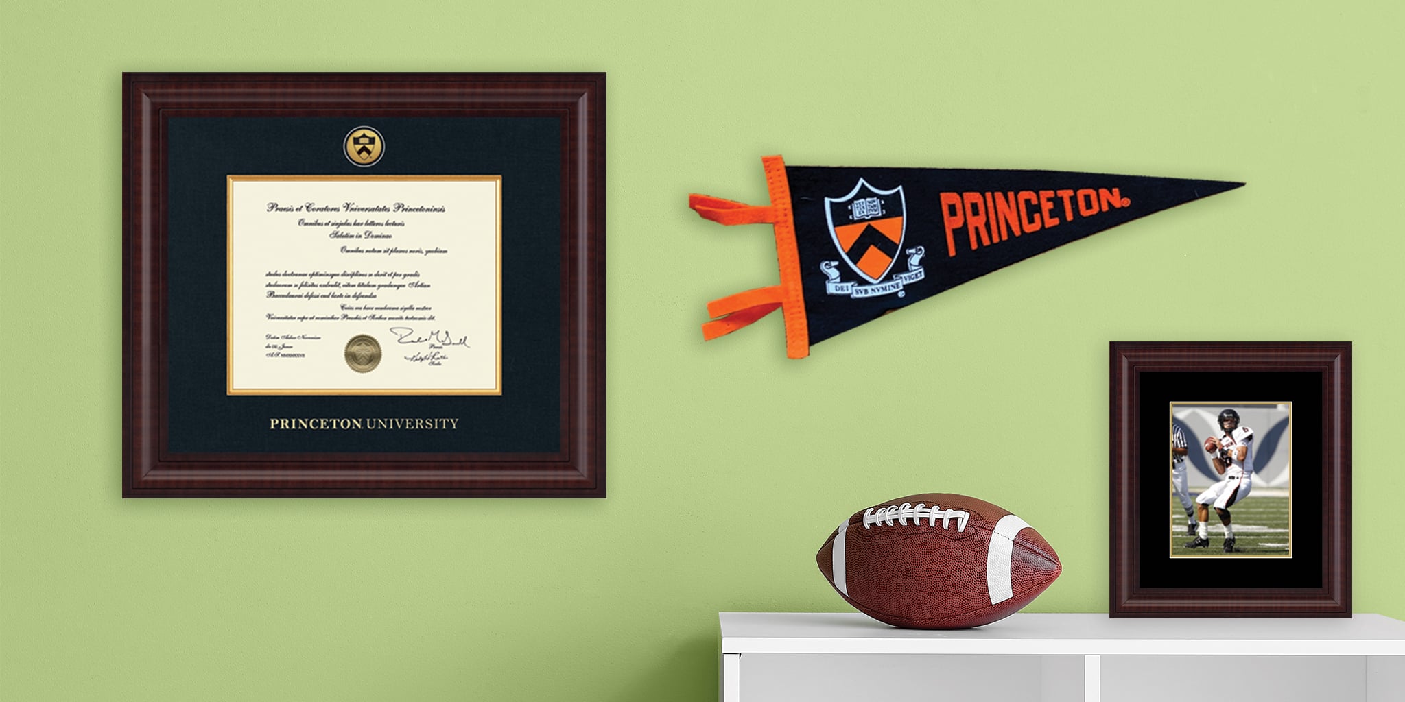 wall with princeton dipolma frame, spirit pennant, and photo frame with football player and football on desk