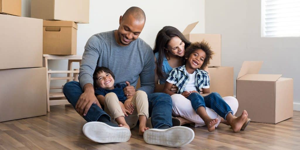 family laughing and sitting with moving boxes